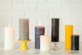 Different decorative wax candles on table