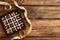 Different delicious chocolate candies in box and ribbon on wooden table, top view. Space for text Royalty Free Stock Photo