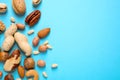 Different delicious nuts on light blue background, flat lay. Space for text Royalty Free Stock Photo