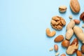Different delicious nuts on light blue background, flat lay. Space for text Royalty Free Stock Photo