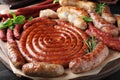 Different delicious sausages with herbs on table, closeup. Assortment of beer snacks Royalty Free Stock Photo