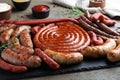 Different delicious sausages with rosemary and sauces on wooden table, closeup. Assortment of beer snacks Royalty Free Stock Photo