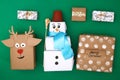 Different design of Christmas gifts from craft paper on a green background. Snowman, deer, stars, snow, handmade text. Handmade,