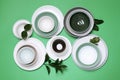 Different dishware and leaves on green background, flat lay