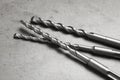 Different drill bits on grey table, closeup