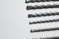 Different drill bits on light background, closeup. Space for text