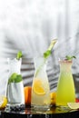 Different drinks in glass jugs on table and shadow of tropic plant on light background. Different drinks in glass jugs with copy Royalty Free Stock Photo