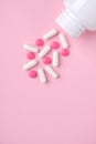 Different drugs falling from the white  bottle on pink paper background. Concept of pharmacy. Royalty Free Stock Photo