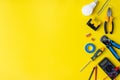 Different electrician`s supplies on yellow background. Background of professional electrician tools with space for text