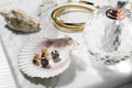 Different elegant bijouterie, shells and bottle of perfume on white table, closeup