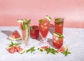 Different elegant glasses with watermelon cocktail. Splash, splatter, water drops on the pink background