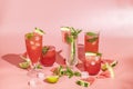 Different elegant glasses with watermelon cocktail. Splash, splatter, water drops on the pink background with sun light