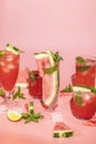 Different elegant glasses with watermelon cocktail. Splash, splatter, water drops on the pink background with sun light