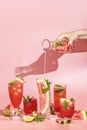 Different elegant glasses with watermelon cocktail, women hand is pouring sparkling water from bottle to glass Royalty Free Stock Photo