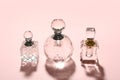 Different elegant perfume bottles on pink