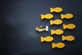 different fish swimming opposite way of identical ones. Courage and success concept. Blackboard background.