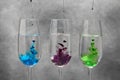 Different food coloring pouring into glasses on grey Royalty Free Stock Photo