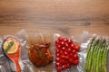 Different food products in vacuum packs on wooden table, flat lay. Space for text