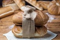 Different fresh baked bread on wooden table. Two loaves tied up together with sackcloth