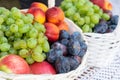 Different fresh fruits in white basket, grapes, apples, peaches and plums Royalty Free Stock Photo