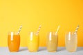 Different fresh juices in glasses on light table against orange background