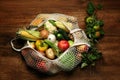 Different fresh vegetables and fruits in net bag on wooden table, top view. Farmer harvesting