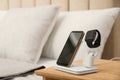 Gadgets charging on wireless pad in bedroom. Space for text Royalty Free Stock Photo