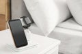 Different gadgets charging on wireless pad in bedroom Royalty Free Stock Photo