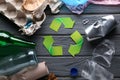 Different garbage with symbol of recycling on grey wooden background. Ecology concept Royalty Free Stock Photo