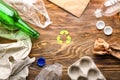 Different garbage with symbol of recycling on wooden background. Ecology concept Royalty Free Stock Photo
