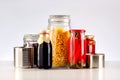 Different glass jars with grains, pasta, vegetable, cans of canned food.