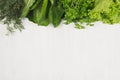 Different green sheaves greens for spring salad on white wooden background, top view, decorative frame.