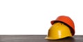 Different hard hats on wooden table against white background. Space for text