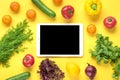 Different health food -  bell pepper, tomatoes, bananas, green cucumber, onions, lemon, tablet with black screen on yellow backgro Royalty Free Stock Photo