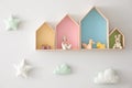 Different house shaped shelves with toys and decorative clouds on wall. Interior design