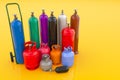 Different industrial liquefied gas cylinders with hand truck on yellow backdrop. 3D rendering