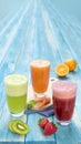 Different Juices in One Group Picture Includes Kiwi Juice, Strawberry Juice, Orange Juice with Carrots Juice. On Blue Wood Royalty Free Stock Photo