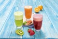 Different Juices in One Group Picture Includes Kiwi Juice, Strawberry Juice, Orange Juice with Carrots Juice. On Blue Wood