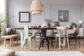 Different kid of chairs at table with flowers and food in rustic dining room interior with lamp and posters. Real photo