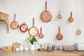 Different kind of cookware and ceramic plates on tabletop wooden kitchen. Set of copper saucepans, pans, pots and ladle hanging in Royalty Free Stock Photo