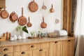 Different kind of cookware and ceramic plates on tabletop wooden kitchen. Set of copper saucepans, pans, pots and ladle hanging in