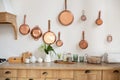 Different kind of cookware and ceramic plates on tabletop wooden kitchen. Set of copper saucepans, pans, pots and ladle hanging in