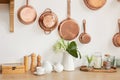 Different kind of cookware and ceramic plates on tabletop wooden kitchen. Set of copper saucepans, pans, pots and ladle hanging in