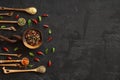 Different kind of spices on a black stone. Oriental spices in spoons, peppers, curry powder, herbs on black metallic tray in Asian Royalty Free Stock Photo