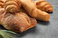 Different kinds of bread rolls on gray board, closeup. Kitchen or poster design for a local bakery. Baguette, croissant and