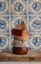 Different kinds of cheese. Assorted cheese tower on a wooden board in in front of a rustic tile wall