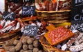 Different kinds of French salami provencale presented in wicker baskets with handwritten chalk boards on farmer market