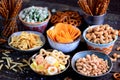 Different kinds of snacks - chips, salted peanuts, cashews, peas with wasabi, pretzels with salt, potatoes, salted straw.