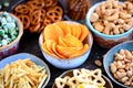 Different kinds of snacks - chips, salted peanuts, cashews, peas with wasabi, pretzels with salt, potatoes, salted straw.