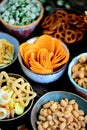 Different kinds of snacks - chips, salted peanuts, cashews, peas with wasabi, pretzels with salt, potatoes, salted straw.